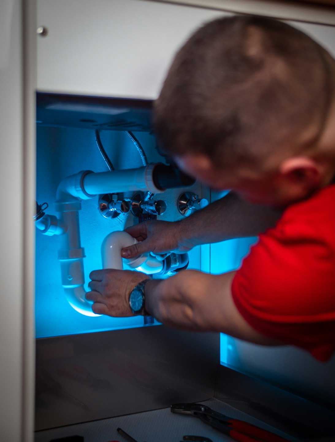 Technician working on PVC plumbing under a sink.